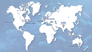 World map graphic showing global office and team locations marked with pins, including California and New York in the United States, France and Germany in Europe, India labeled as remote, and Australia, displayed on a blue background with subtle network connection patterns indicating global reach and collaboration.