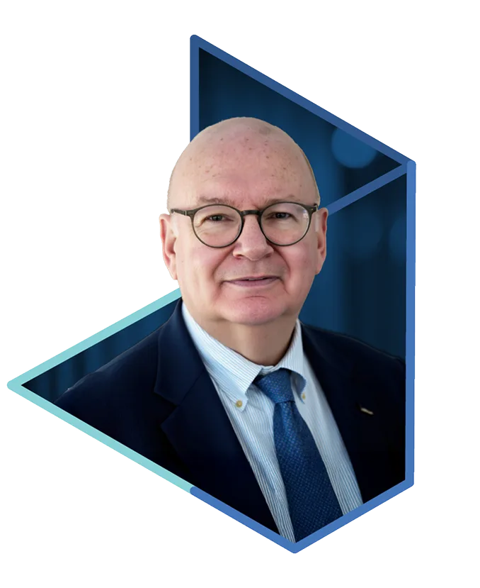 Professional headshot of a bald man wearing glasses, a navy blazer, and a blue tie, smiling against a blurred blue background.